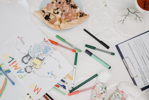 A colorful child's drawing of a family alongside pizza and pens on a table.